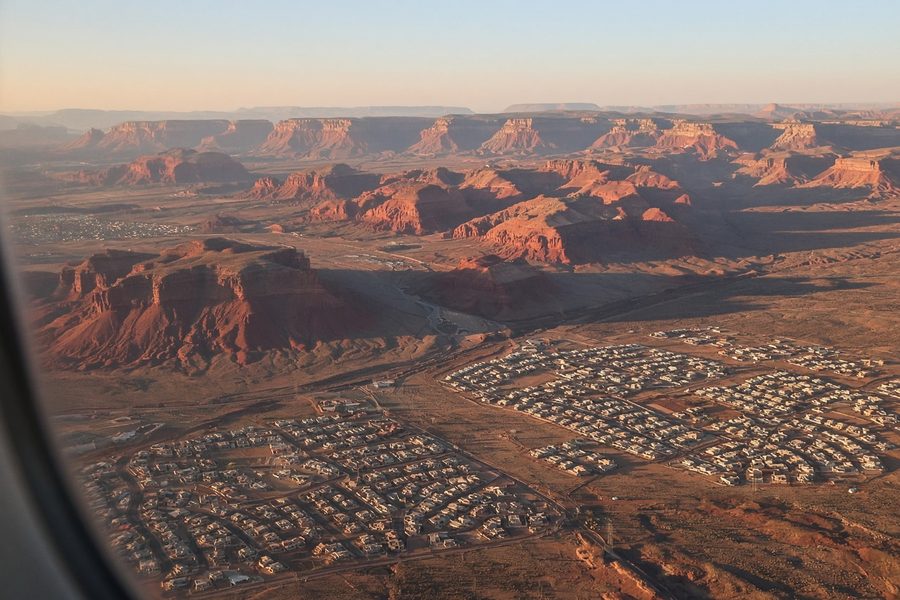 Desert neighborhood rooftops seen from an airplane window
